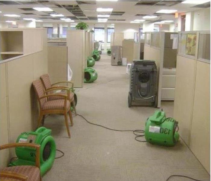 open ceiling removed tiles, carpeted walkway with drying equipment between cubicles.