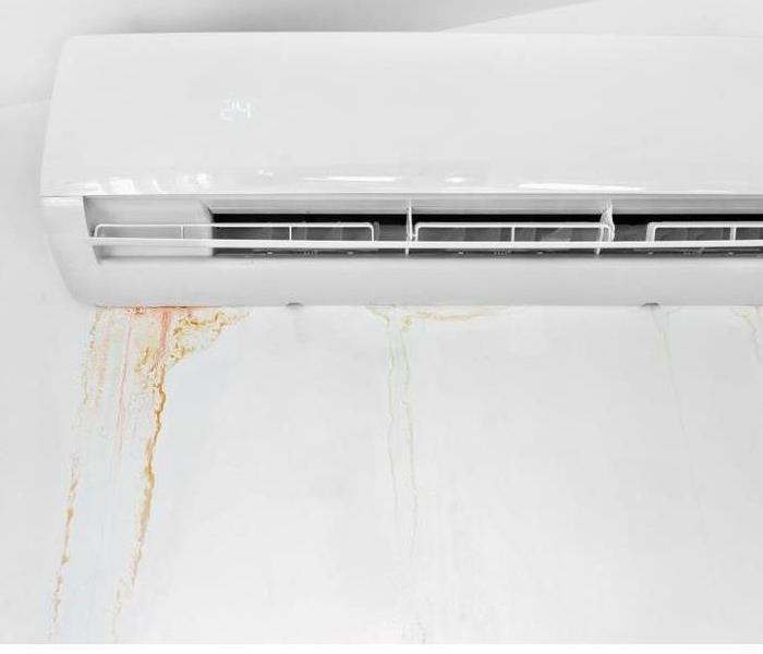 A closeup of an air conditioning unit with questionable water damage stains around it