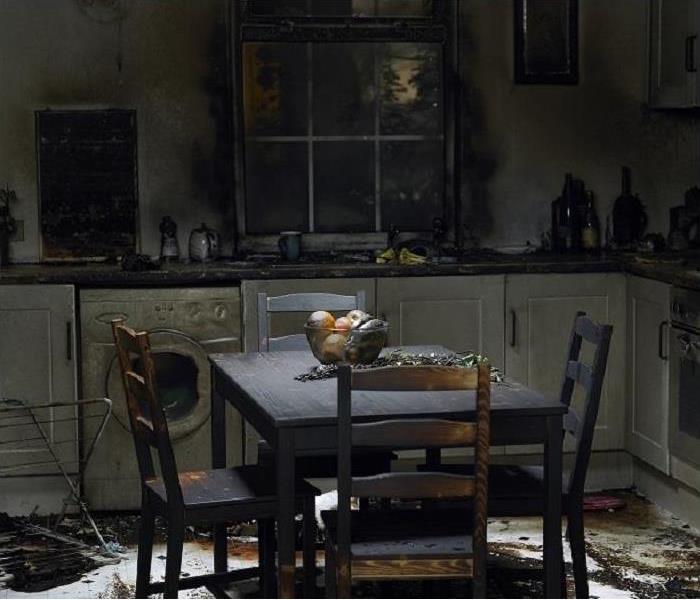 fire damaged kitchen; charred table; smoke and soot on walls and cabinets